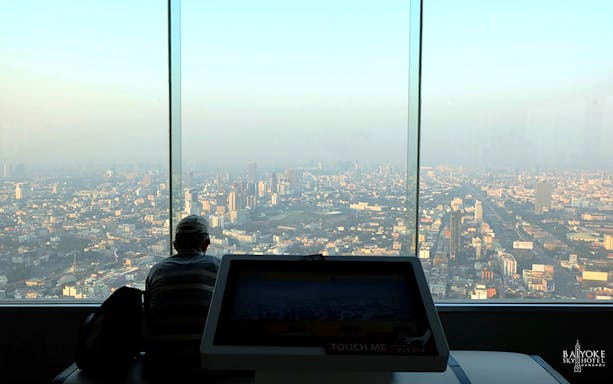 Baiyoke Sky Hotel observatory view of Bangkok cityscape through large windows.