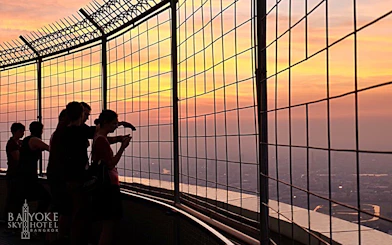 Visitors at Baiyoke Sky Hotel Observatory enjoying sunset views over Bangkok.