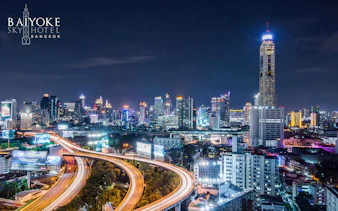 Bangkok skyline at night with Baiyoke Sky Hotel towering above city lights.