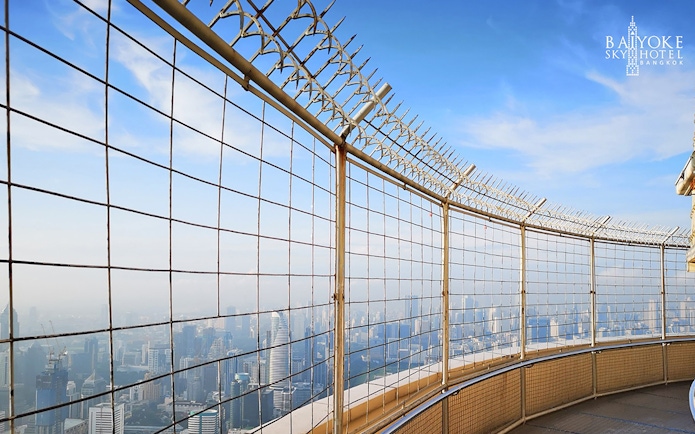 Baiyoke Sky Hotel observatory view of Bangkok skyline through safety fence.