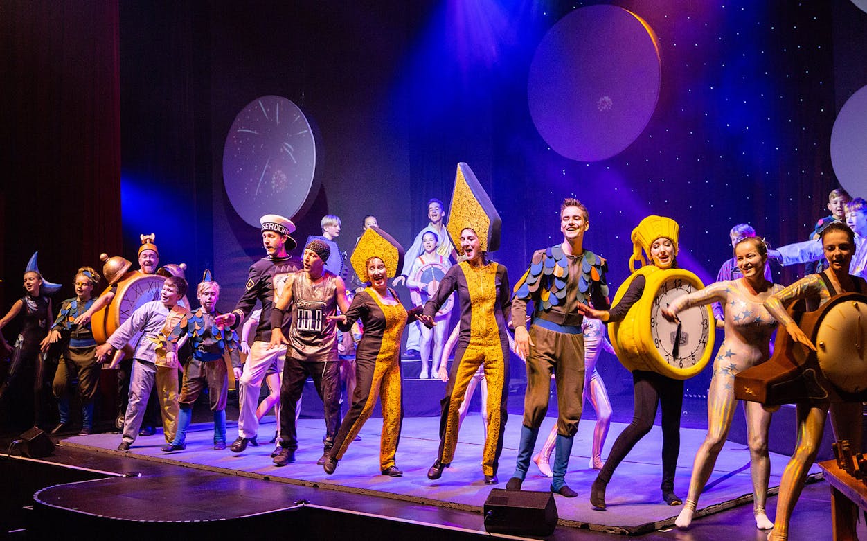Performers in colorful costumes on stage during "Peter and Anneli's Journey to the Moon" show.