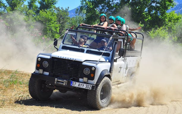 Off-road vehicle with tourists on a dusty trail in Koprulu Canyon.