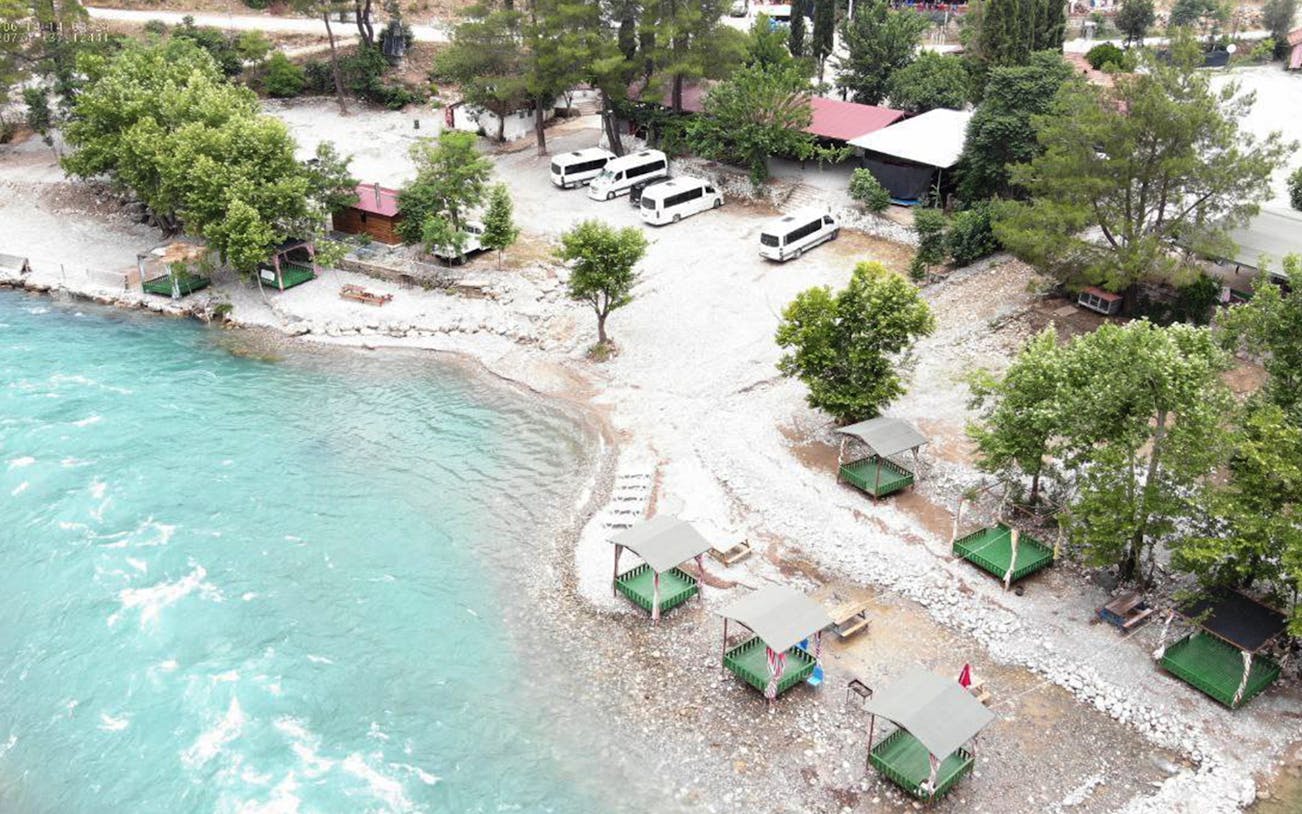 Koprulu Canyon riverside with picnic areas and parked vans for whitewater rafting tour.
