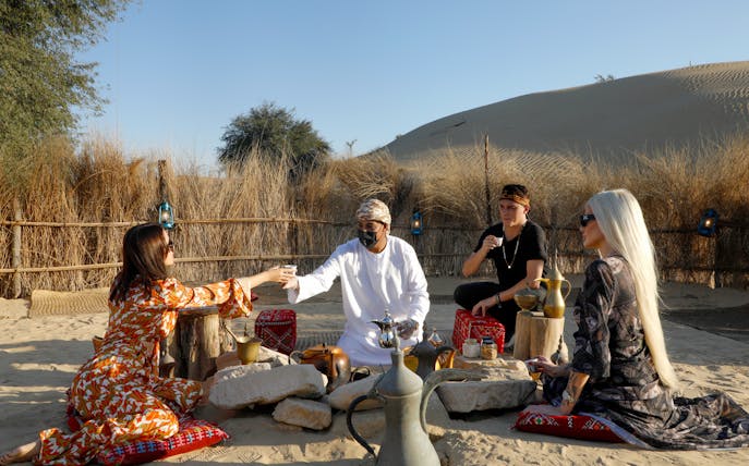 Morning tea ceremony at Al Marmoom Oasis with guests seated on cushions in the desert.