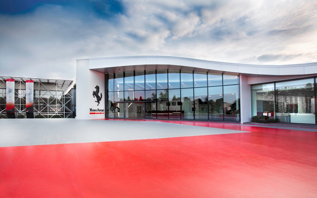 Ferrari Museum Maranello entrance with red pavement and modern glass facade.