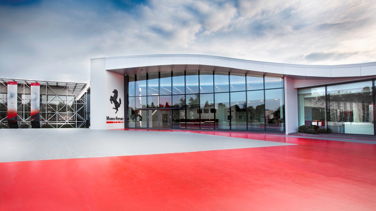 Ferrari Museum Maranello entrance with red pavement and modern glass facade.