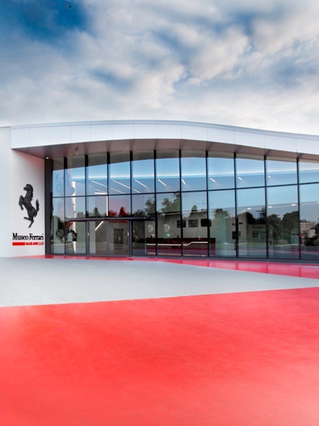 Ferrari Museum Maranello entrance with red pavement and modern glass facade.
