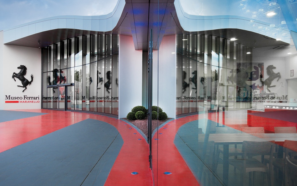 Ferrari Museum Maranello entrance with iconic prancing horse logo and modern glass facade.