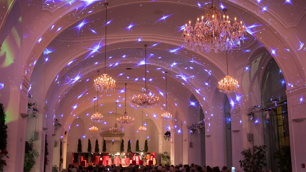 Concert hall in Schönbrunn Palace with chandeliers and audience, Vienna.