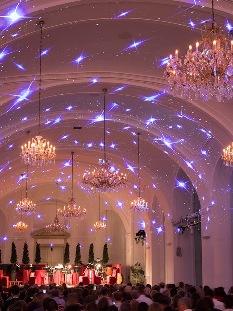 Concert hall in Schönbrunn Palace with chandeliers and audience, Vienna.