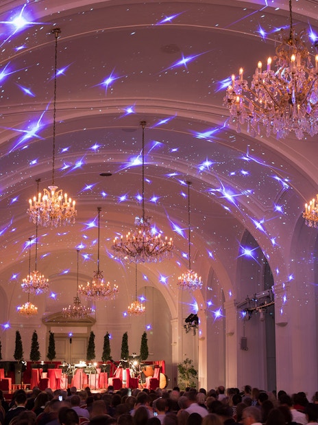 Concert hall in Schönbrunn Palace with chandeliers and audience, Vienna.