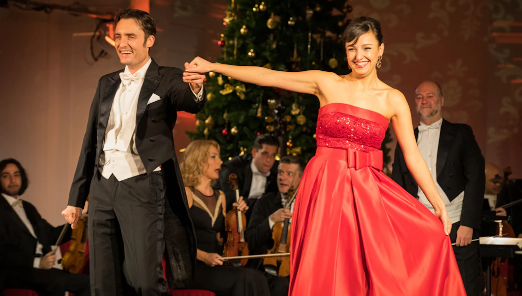 Performers at Mozart and Strauss concert in Schönbrunn Palace with orchestra in background.