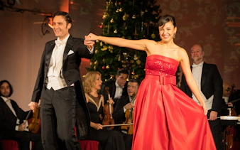 Performers at Mozart and Strauss concert in Schönbrunn Palace with orchestra in background.