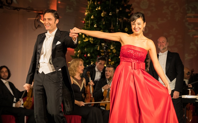 Performers at Mozart and Strauss concert in Schönbrunn Palace with orchestra in background.