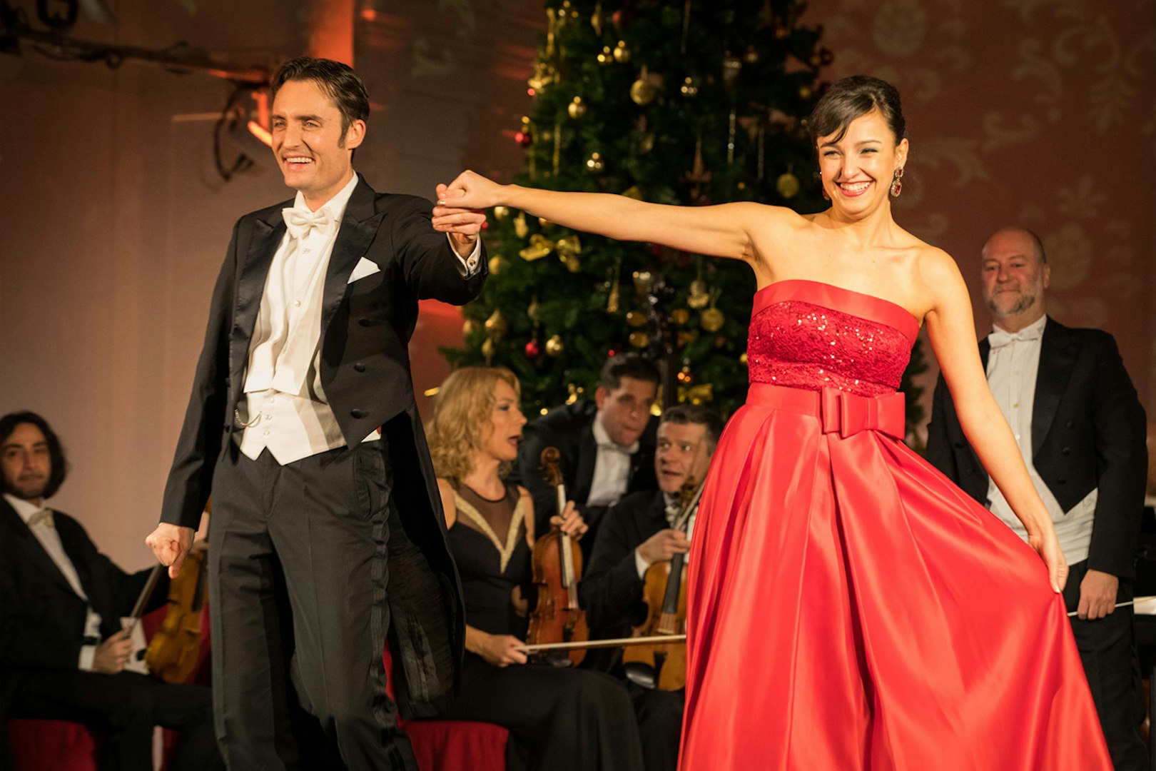 Performers at Mozart and Strauss concert in Schönbrunn Palace with orchestra in background.