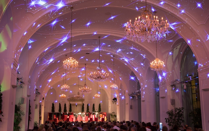 Concert hall in Schönbrunn Palace with chandeliers and audience for Mozart & Strauss performance.