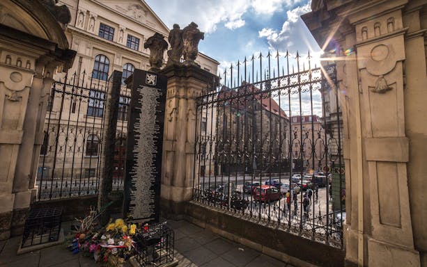 Memorial plaque and flowers at historical site in Prague.