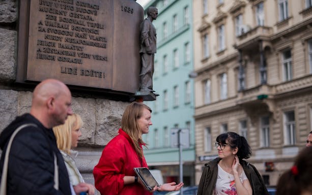 Tour guide explaining historical monument to a small group in Prague.