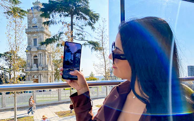 Woman on Istanbul bus tour photographing Dolmabahçe Clock Tower.