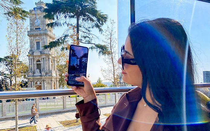 Woman on Istanbul bus tour photographing Dolmabahçe Clock Tower.