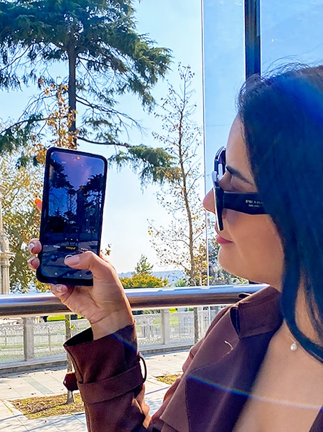 Woman on Istanbul bus tour photographing Dolmabahçe Clock Tower.