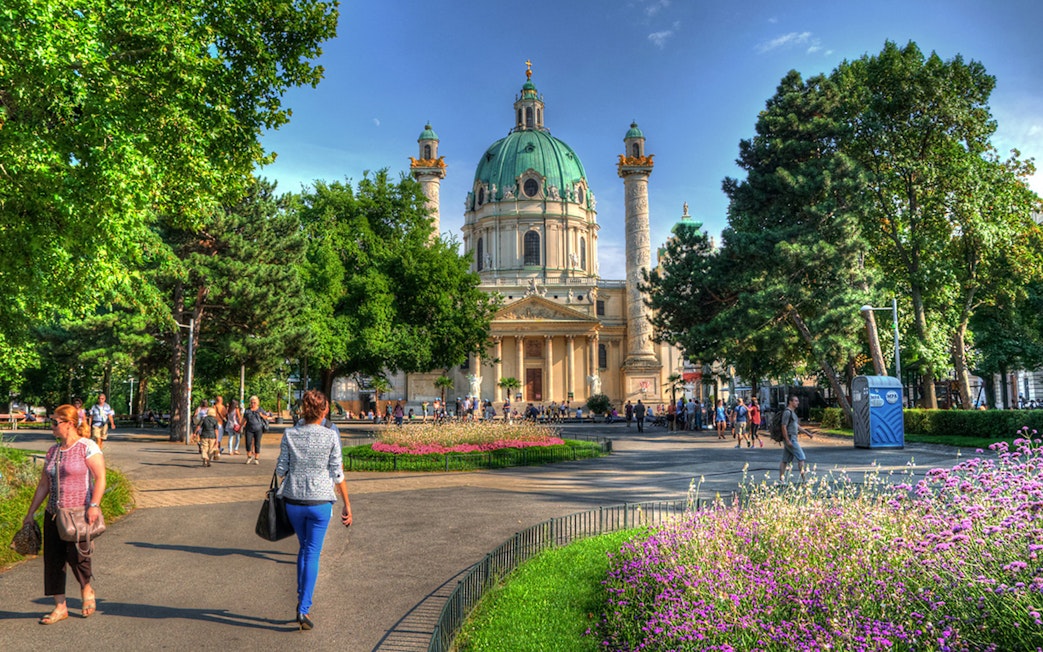 Karlskirche in Vienna with people walking in the garden, location for Vivaldi’s Four Seasons concert.