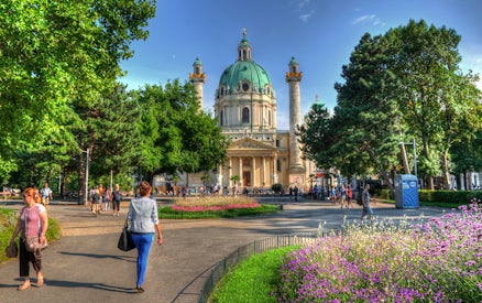 Karlskirche in Vienna with people walking in the garden, location for Vivaldi’s Four Seasons concert.