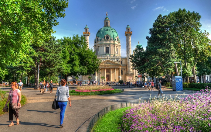 Karlskirche in Vienna with people walking in the garden, location for Vivaldi’s Four Seasons concert.