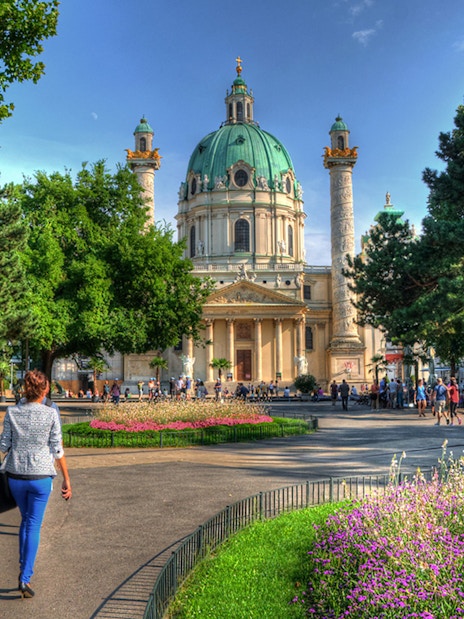 Karlskirche in Vienna with people walking in the garden, location for Vivaldi’s Four Seasons concert.