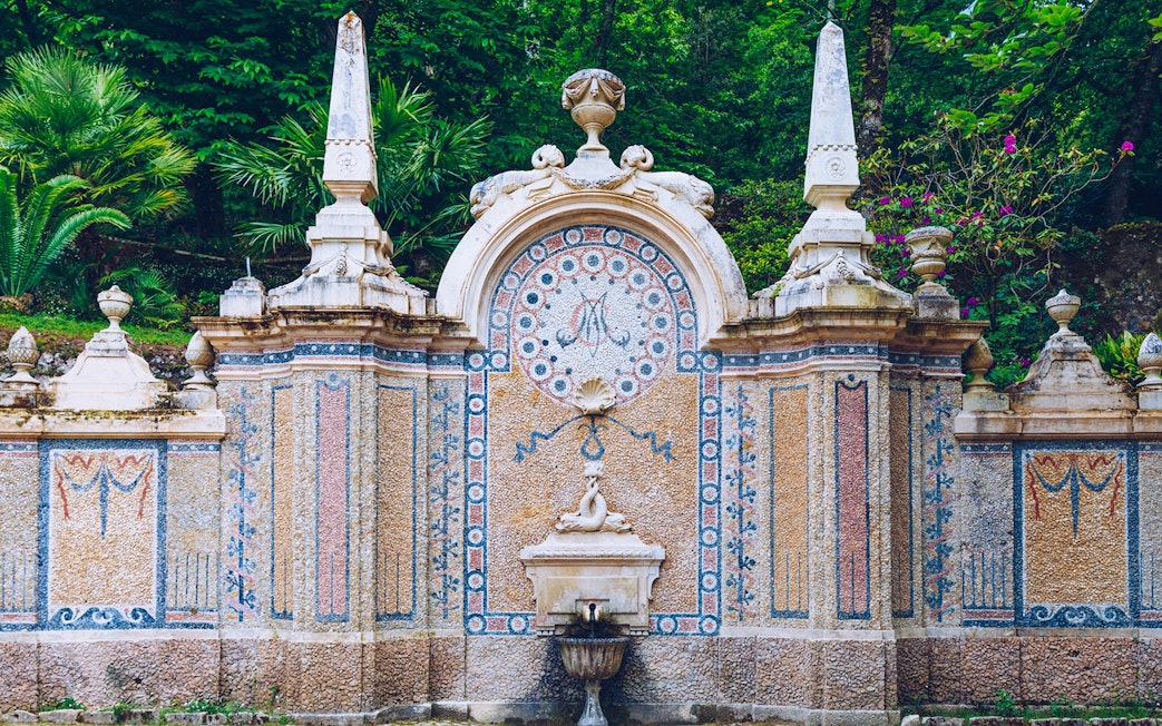 Ornate stone fountain with mosaic details at Quinta da Regaleira, Sintra.