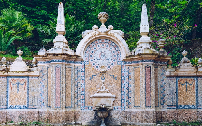 Ornate stone fountain with mosaic details at Quinta da Regaleira, Sintra.