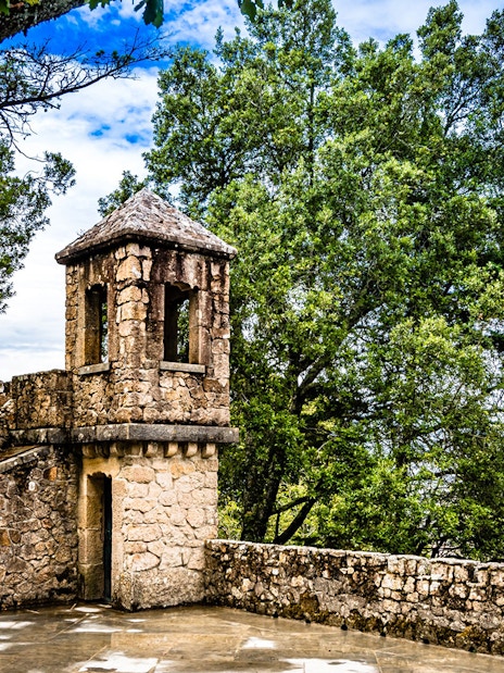 Stone tower at Quinta da Regaleira surrounded by lush greenery, Sintra, Portugal.