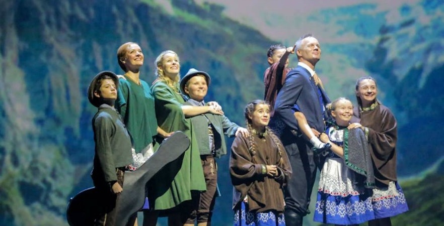 Cast performing The Sound of Music musical on stage with mountain backdrop.