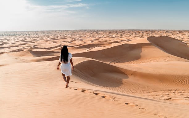 Person walking on sand dunes during Doha Half-Day Desert Safari.