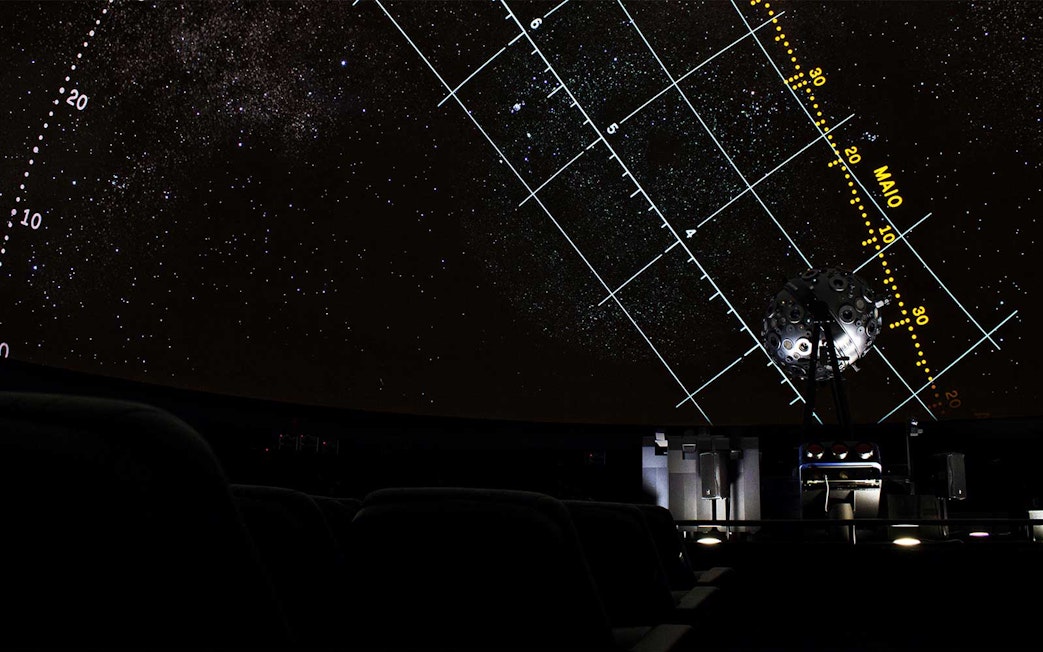Starry projection inside Navy Planetarium with celestial grid lines.