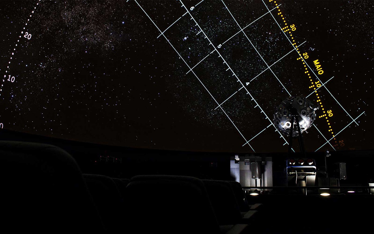Starry projection inside Navy Planetarium with celestial grid lines.