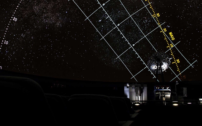 Starry projection inside Navy Planetarium with celestial grid lines.