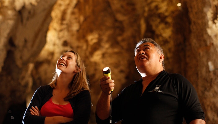 Visitors exploring a tunnel guide holding a flashlight.