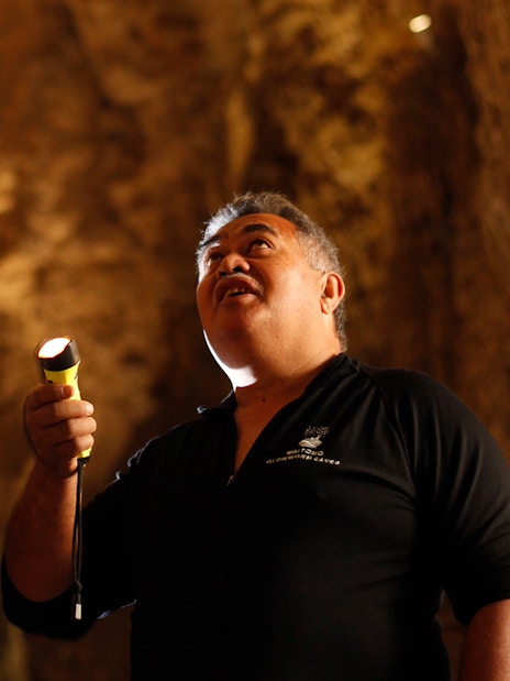 Visitors exploring Waitomo Glowworm Caves with a guide holding a flashlight.