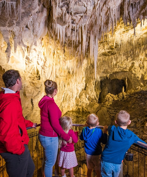 Family exploring stalactites in Waitomo Glowworm Caves, New Zealand.