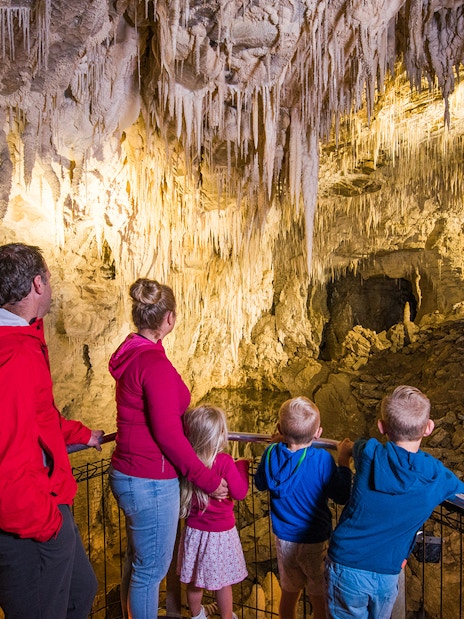 Family exploring stalactites in Waitomo Glowworm Caves, New Zealand.