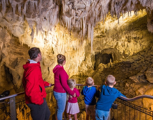 Family exploring stalactites in Waitomo Glowworm Caves, New Zealand.