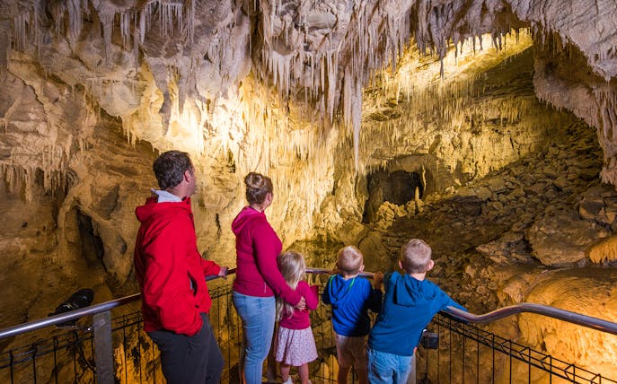 Family exploring stalactites in Waitomo Glowworm Caves, New Zealand.