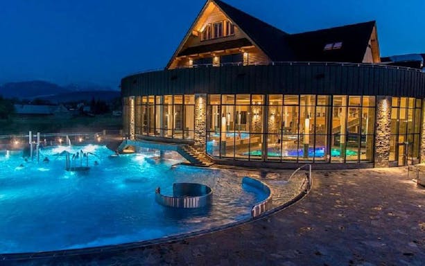 Chocholow Thermal Baths illuminated at night with outdoor pools and modern architecture.