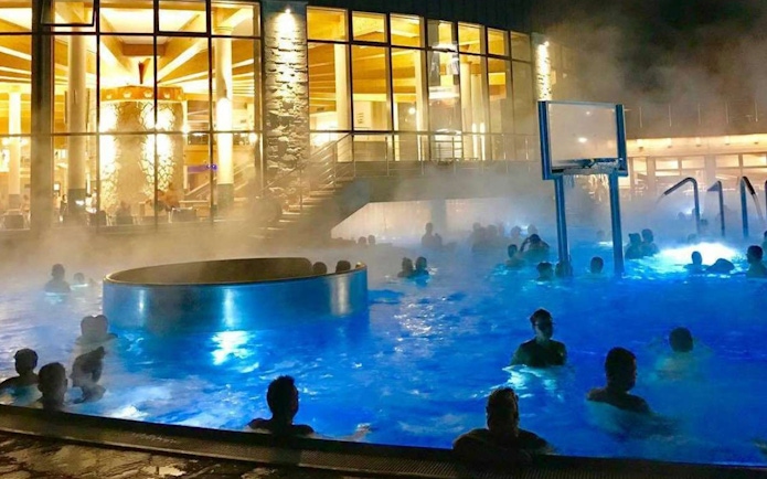 Visitors enjoying the illuminated pools at Chocholow Thermal Baths at night.