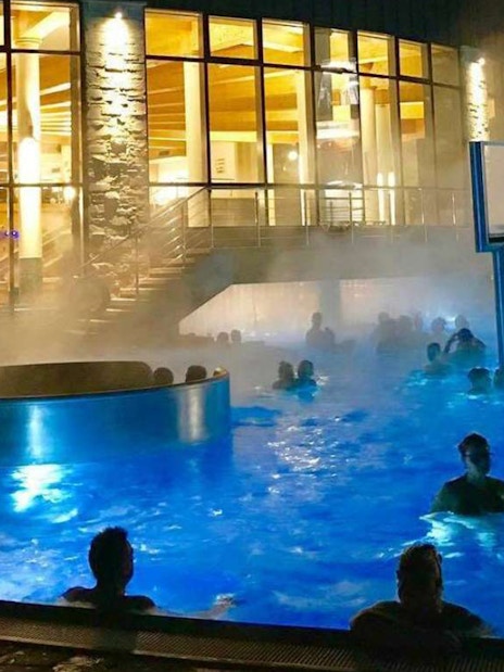 Visitors enjoying the illuminated pools at Chocholow Thermal Baths at night.