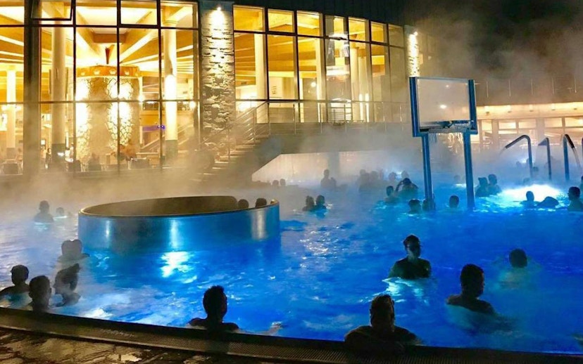 Visitors enjoying the illuminated pools at Chocholow Thermal Baths at night.