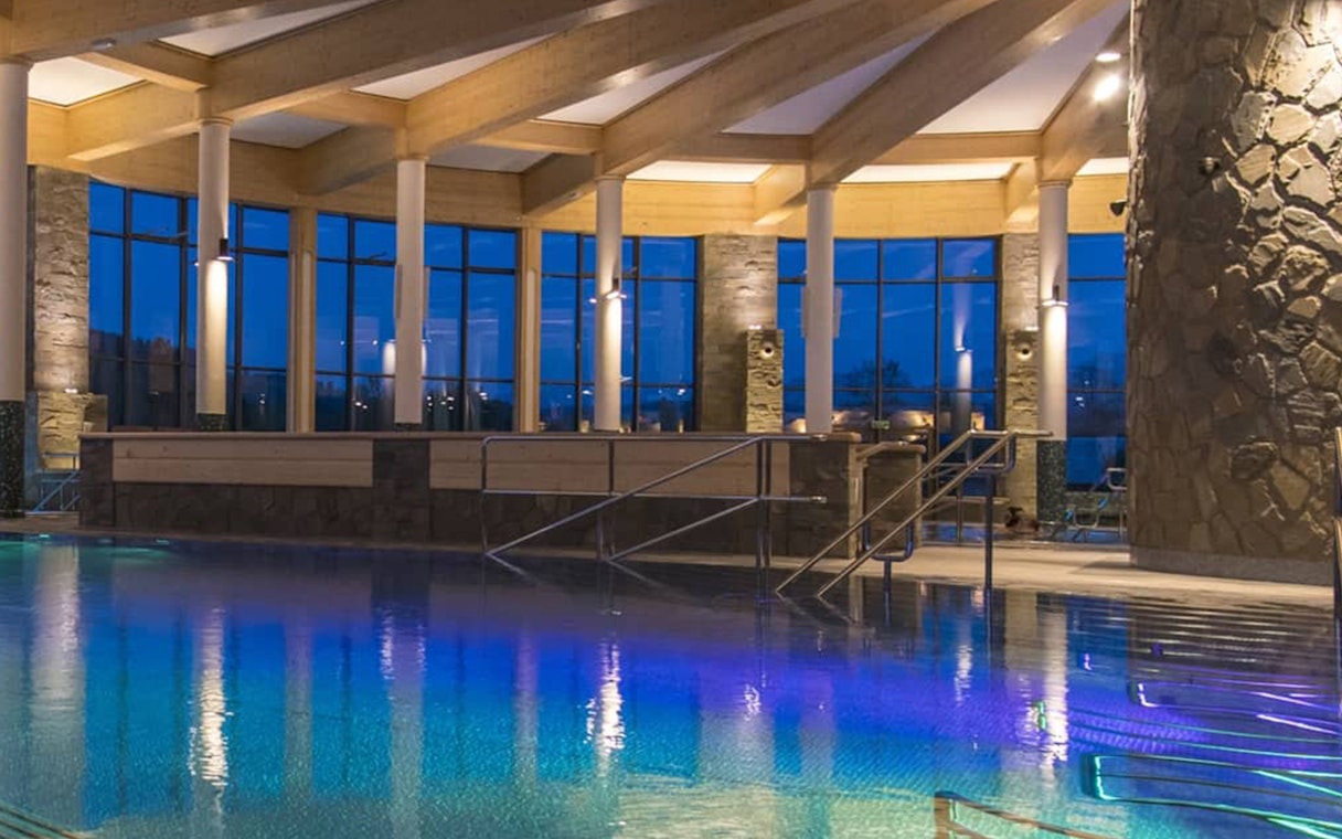 Indoor pool area at Chocholow Thermal Baths with large windows and stone pillars.