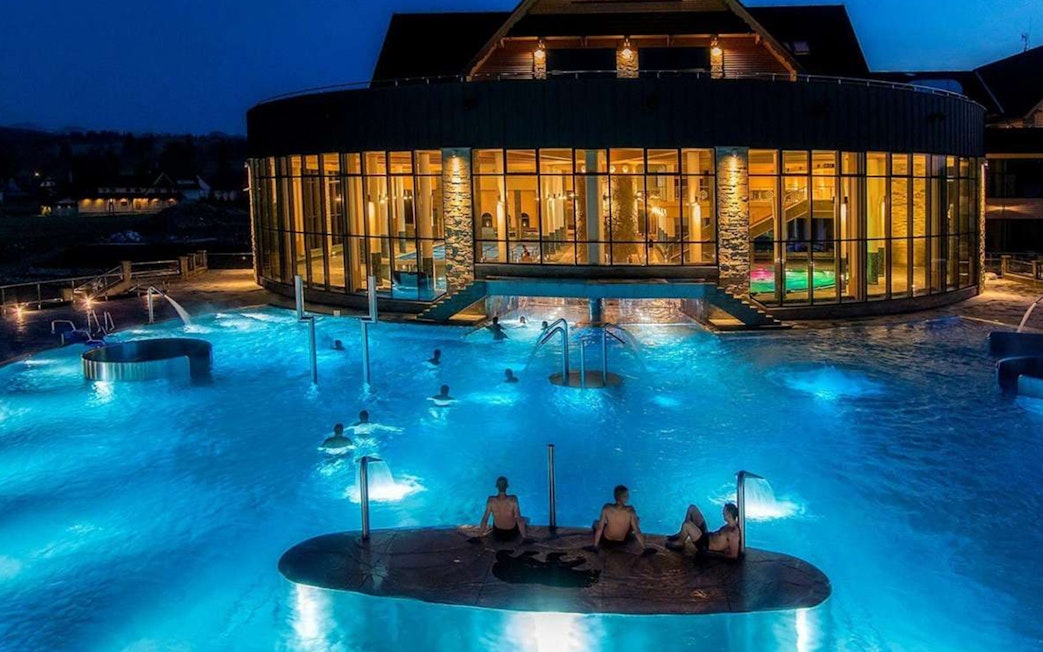 Chocholow Thermal Baths' Saunarium at night with illuminated pools and visitors.