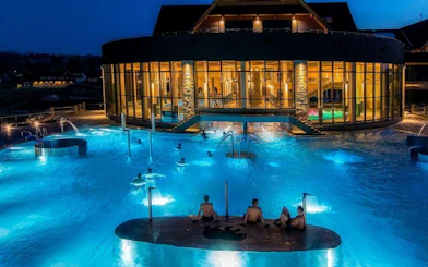 Chocholow Thermal Baths' Saunarium at night with illuminated pools and visitors.
